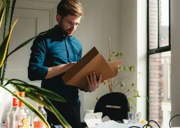 a man standing in an office holding a box