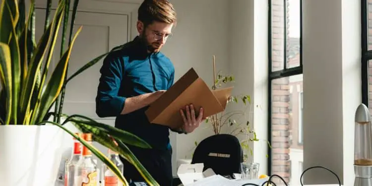 a man standing in an office holding a box