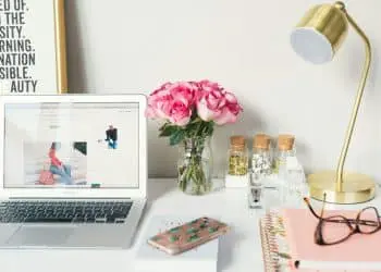 MacBook Air beside gold-colored study lamp and spiral books